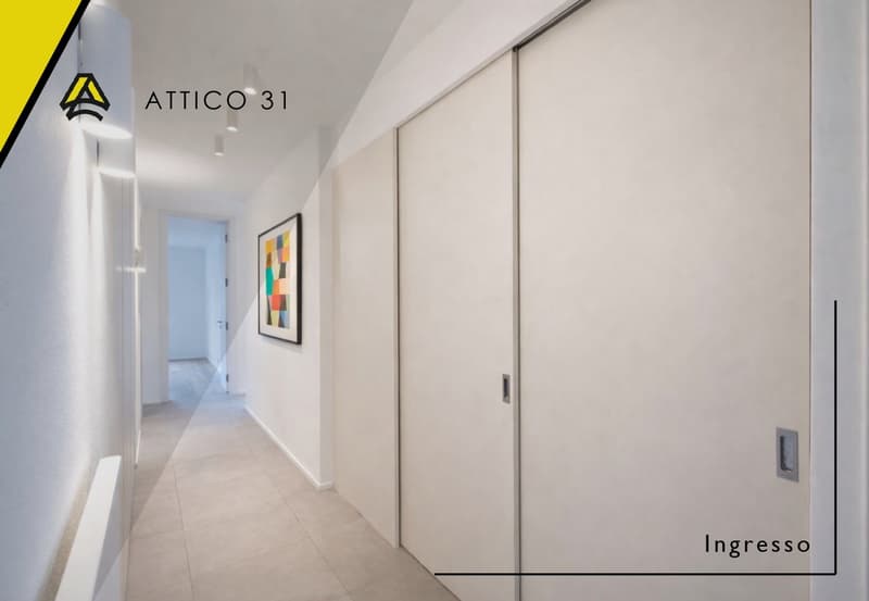 Empty hallway with white walls, tiled floor, sliding doors, and a framed picture on the wall.