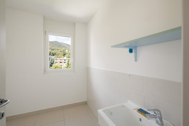 Bathroom with white tiles, white sink, window with view of mountains