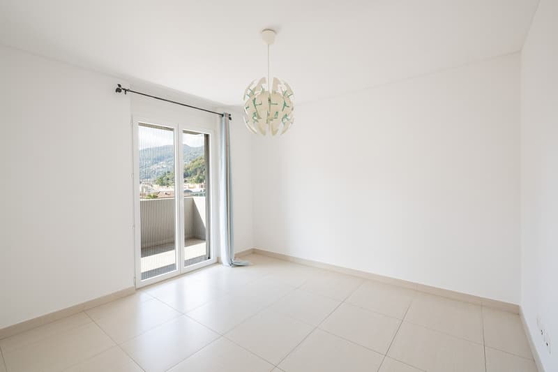 empty room, white walls, white tile flooring, sliding glass door, balcony, chandelier