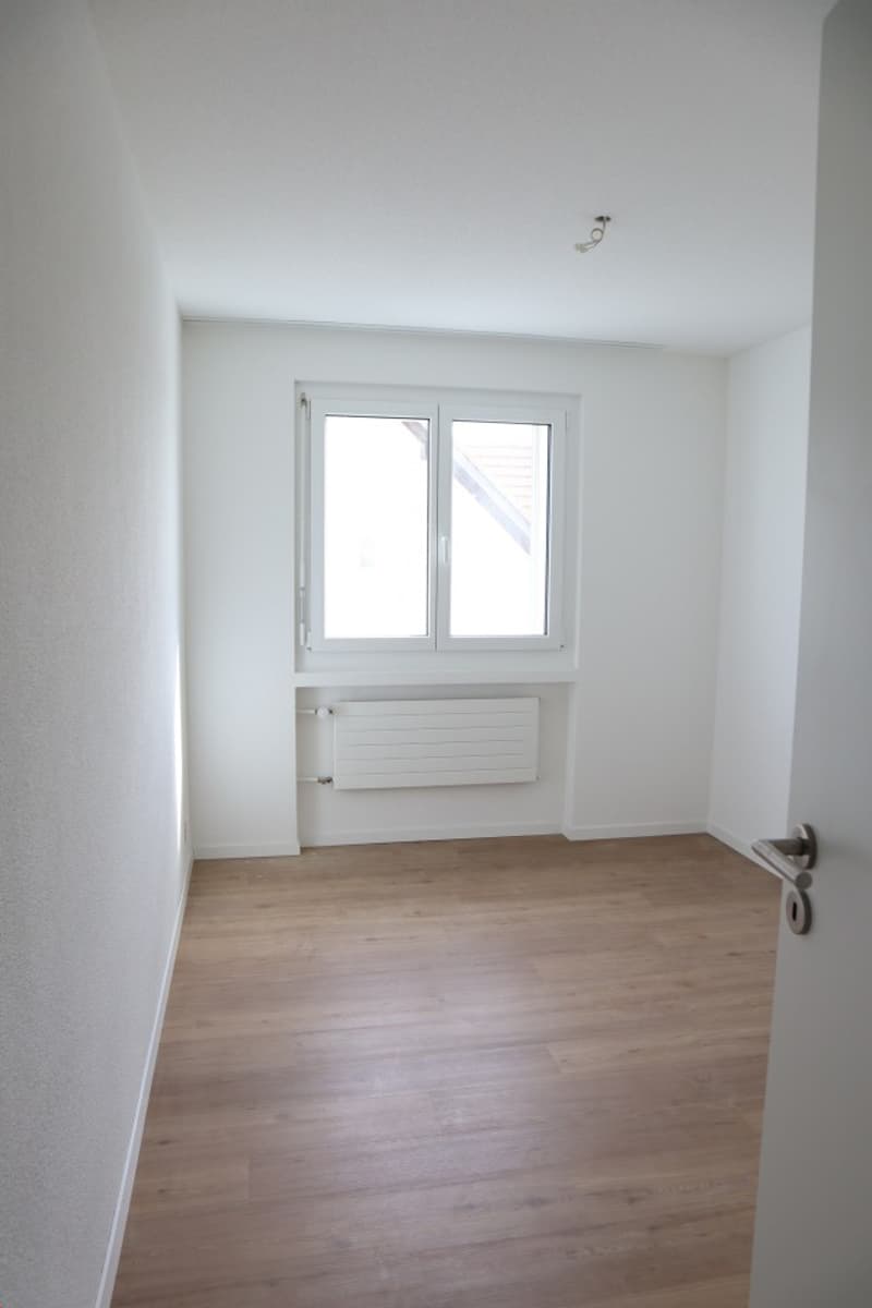 empty room, white walls, wooden floor, window, radiator