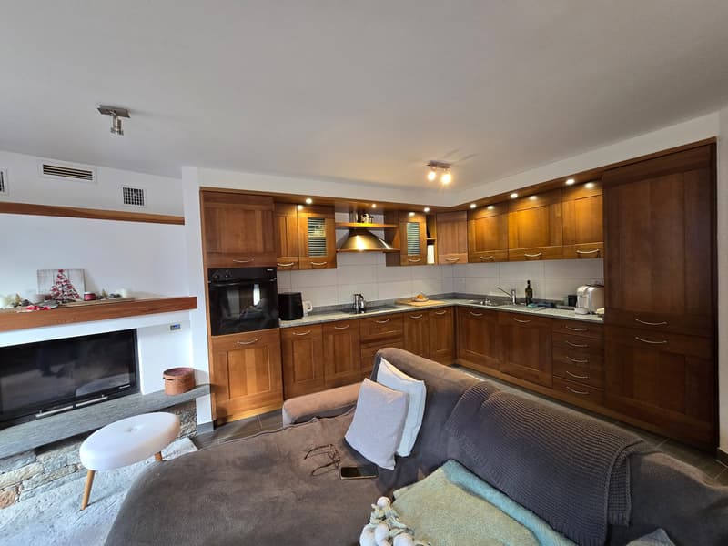 modern living room with fireplace, wooden cabinets, modern kitchen, couch, coffee table, stool
