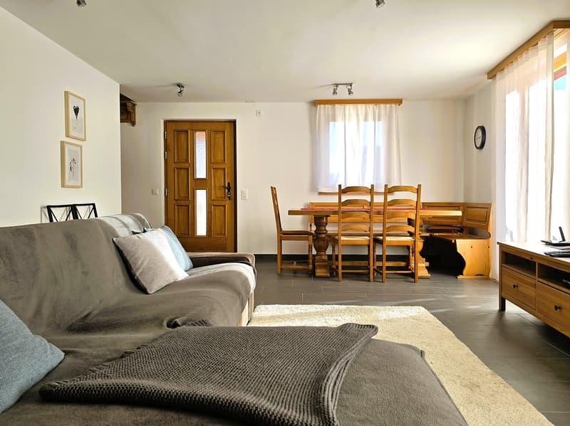 large sofa, dining table, wooden chairs, wooden door, white walls, white curtains, wooden floor, wooden cabinet, TV