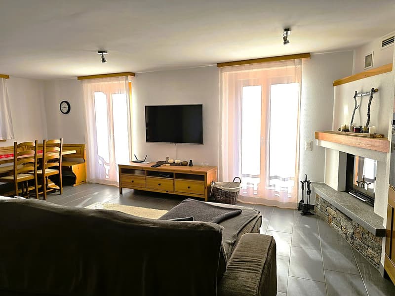 Fireplace, flat screen TV, wooden table, wooden chairs, wooden cabinet, basket, couch, rug