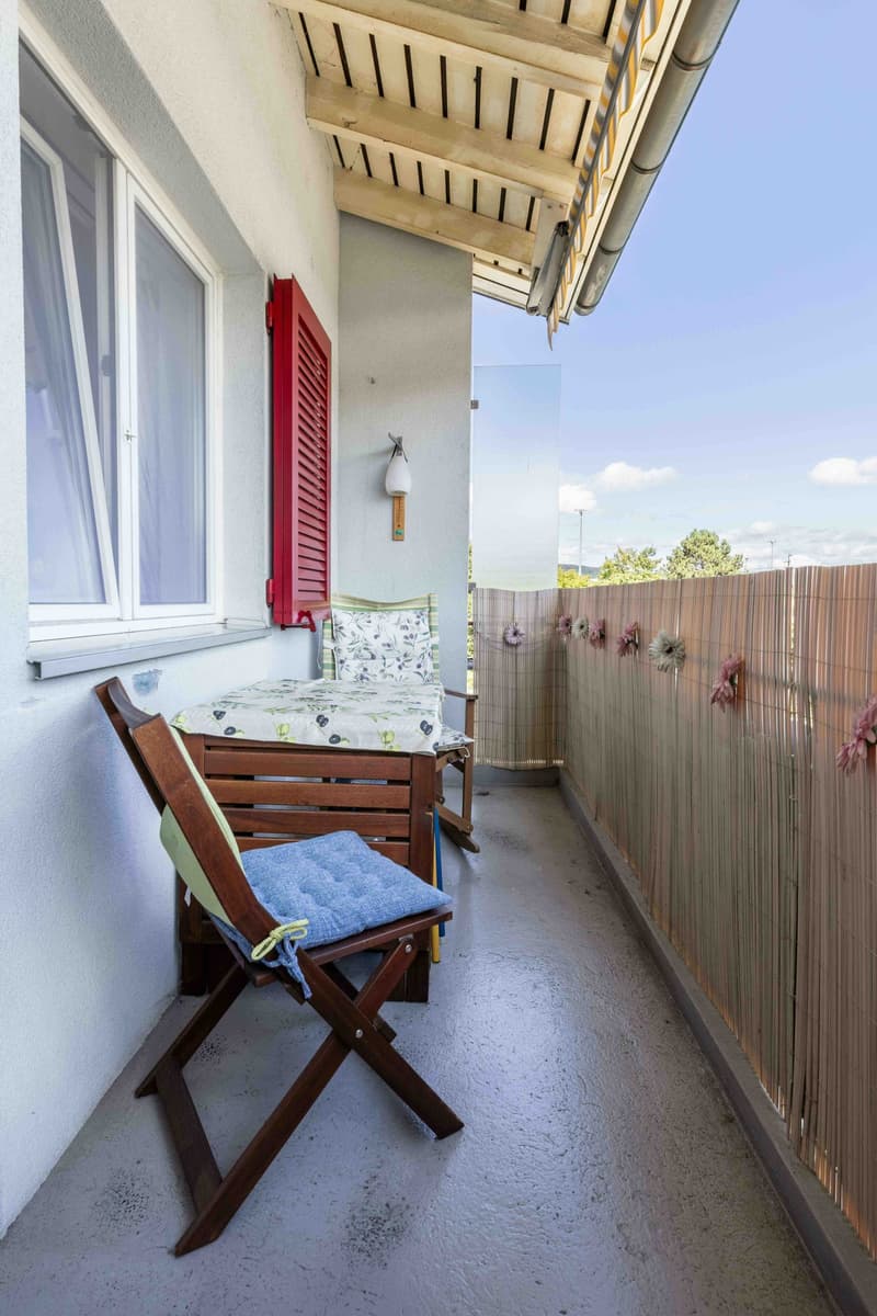 wooden chair, table, pillows, wall lamp, bamboo fence, white windows, red shutters