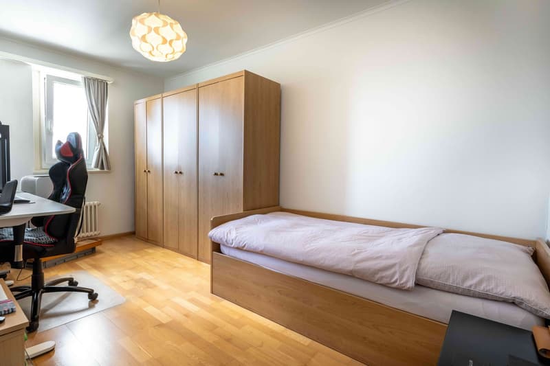 bedroom with bed, desk, chair, radiator, wooden wardrobe, lamp