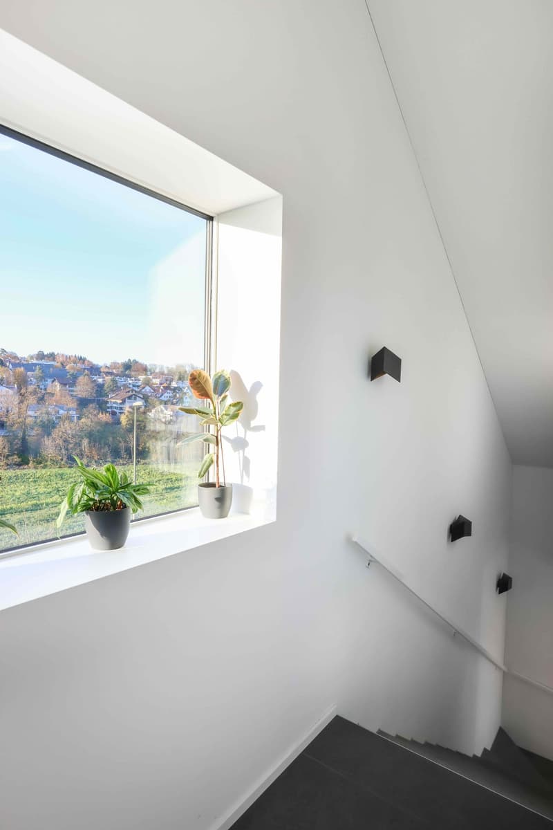 Staircase with window, handrail, and wall lamps
