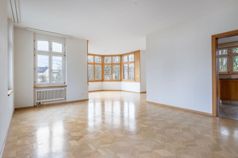 spacious room, wooden parquet floor, large bay windows, white walls, radiator, view