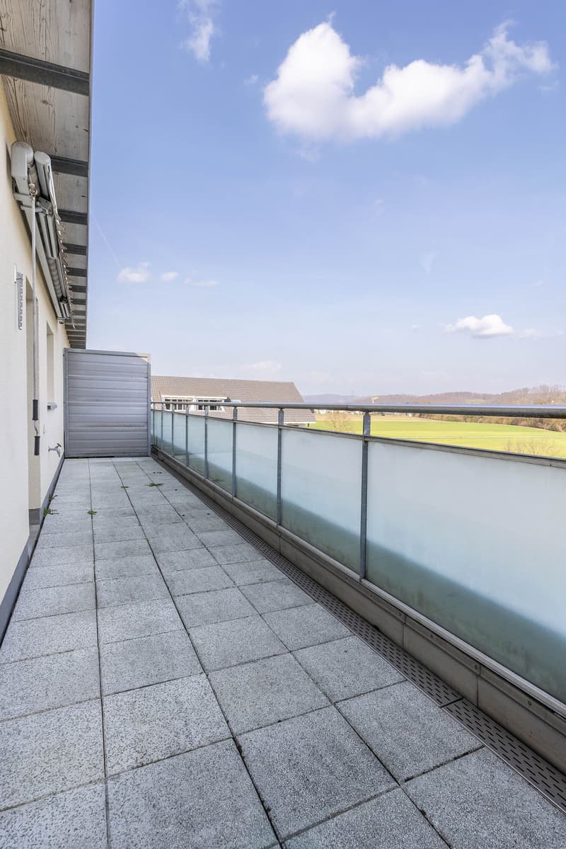 Balcony with tiled floor, metal railing, and a view of a field
