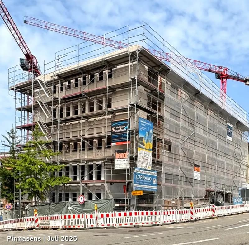 Under construction building, scaffolding, cranes, multiple floors, glass windows, advertisement banners