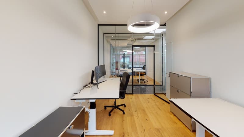 modern office room with white walls, wooden floor, glass walls, desks, chairs, monitors, cabinets