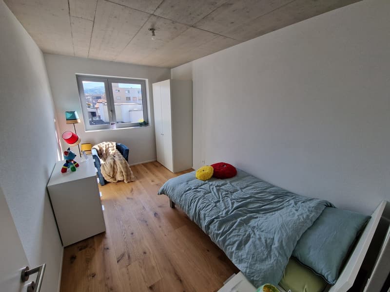 small bedroom with bed, window, wardrobe, wooden floor, lamp, toys