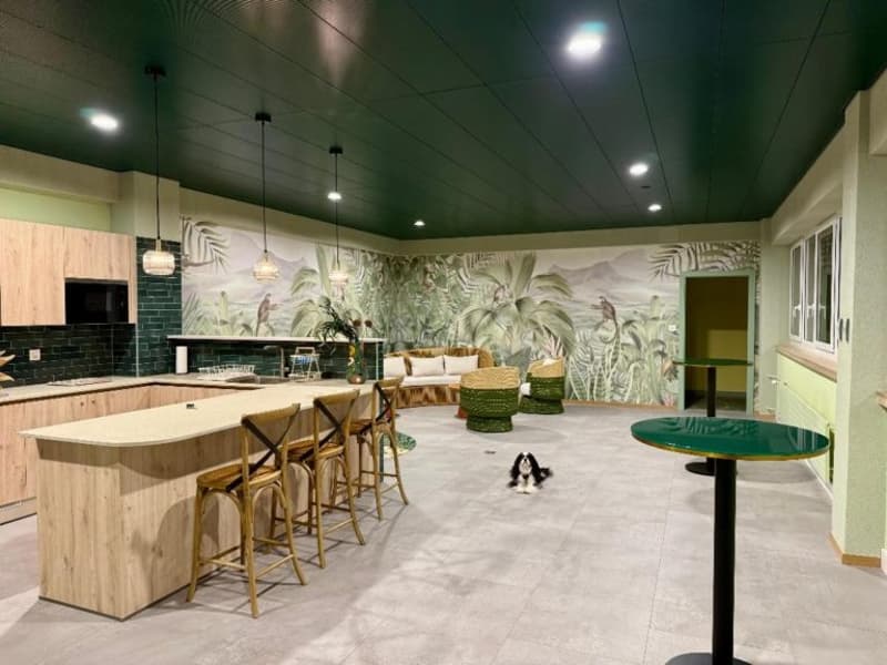 Open kitchen with island, dining area with bar stools, living area with couch, tropical wallpaper, dog