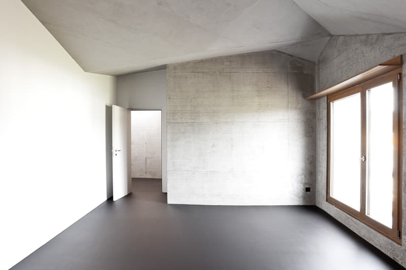 Empty room with white walls, concrete floor, large window, open door