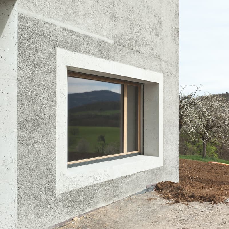 Concrete wall, large window, view of a green field and mountains