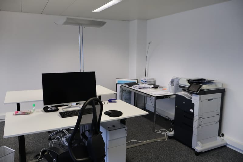 An office with two desks, a computer monitor, keyboard, mouse, and a printer.