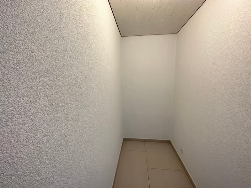 Empty room with white walls, tiled floor, and a ceiling with a wooden texture.