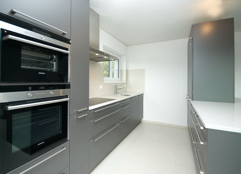 modern kitchen with Siemens oven, Siemens dishwasher, granite countertops, stainless steel appliances, gray cabinets, white backsplash, white tile flooring