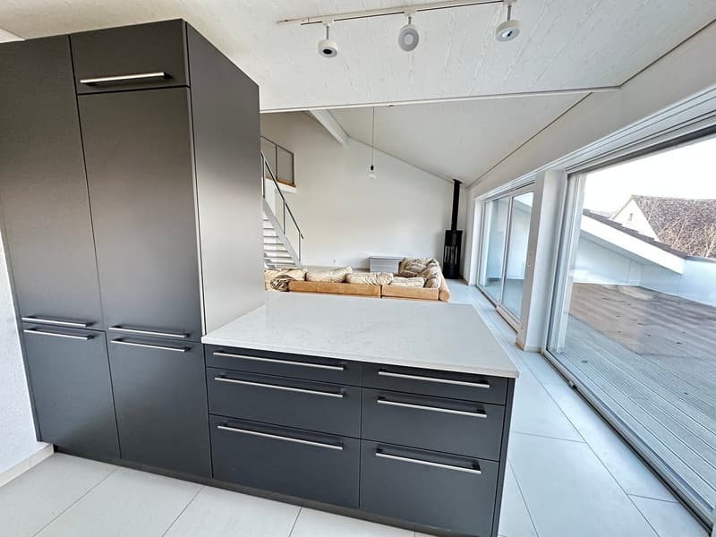 modern kitchen with marble countertop, gray cabinets, large windows, staircase, living room with couch