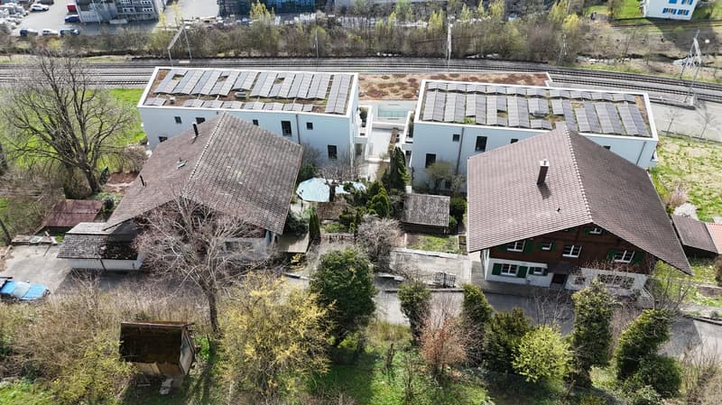 Three houses, two with solar panels on the roof, one with a swimming pool