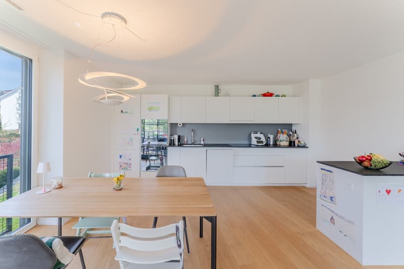 modern kitchen with dining area, wooden table, white cabinets, large windows, balcony