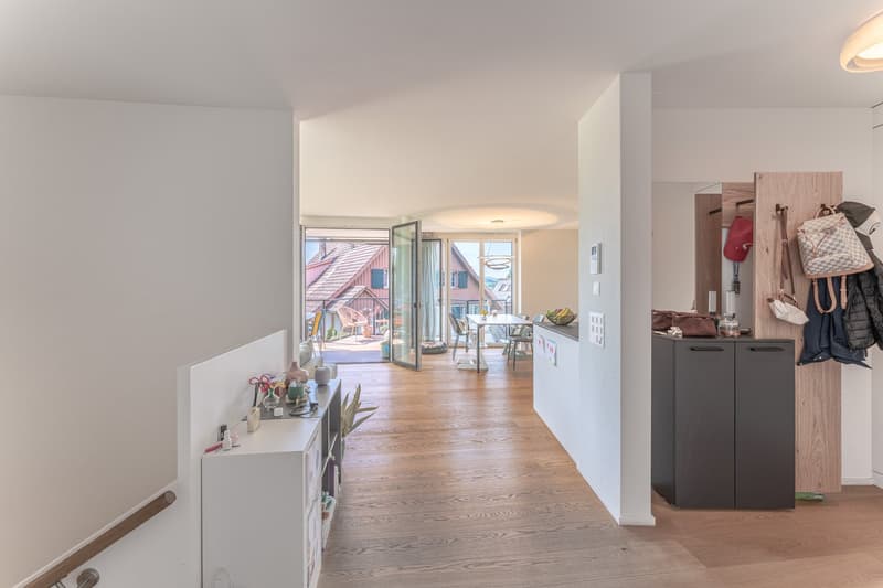 wooden floor, white walls, open door to balcony, table and chairs, coat rack with bags