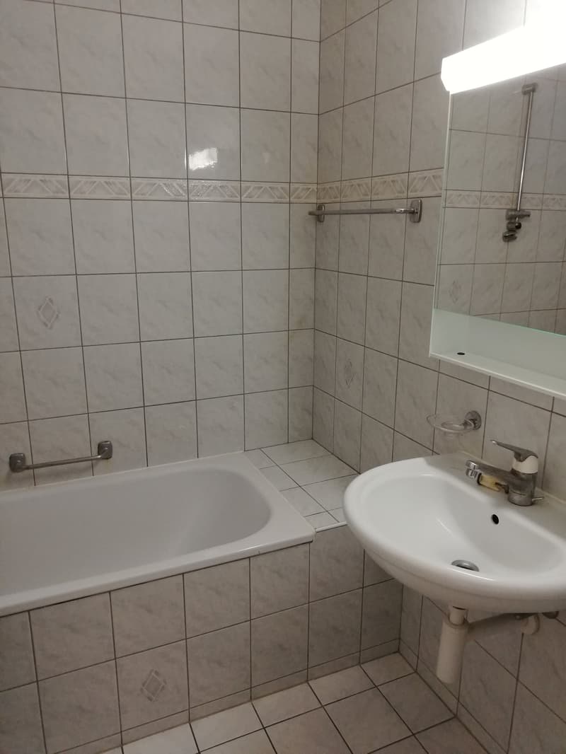 Bathroom with bathtub, sink, mirror, shower bar, light over mirror