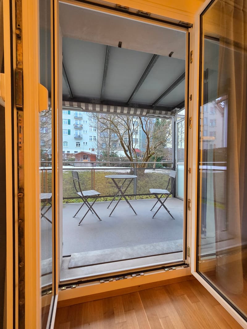 an open balcony with folding doors, a small round table, and 3 folding chairs