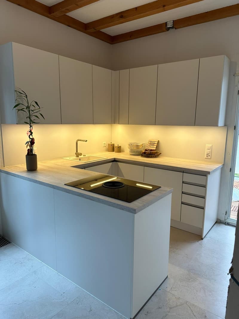 Modern kitchen with white cabinets, black stove, and marble countertop