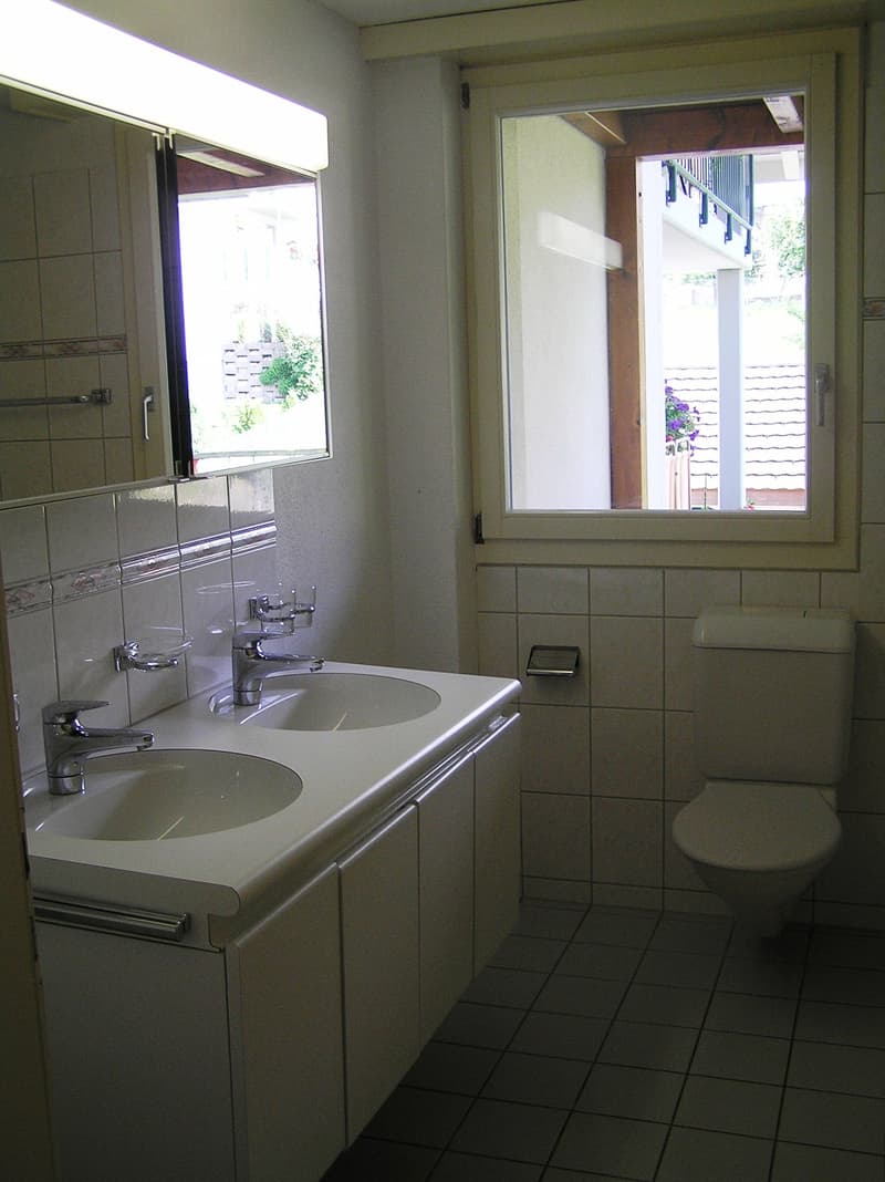 Bathroom with two sinks, toilet, and a window
