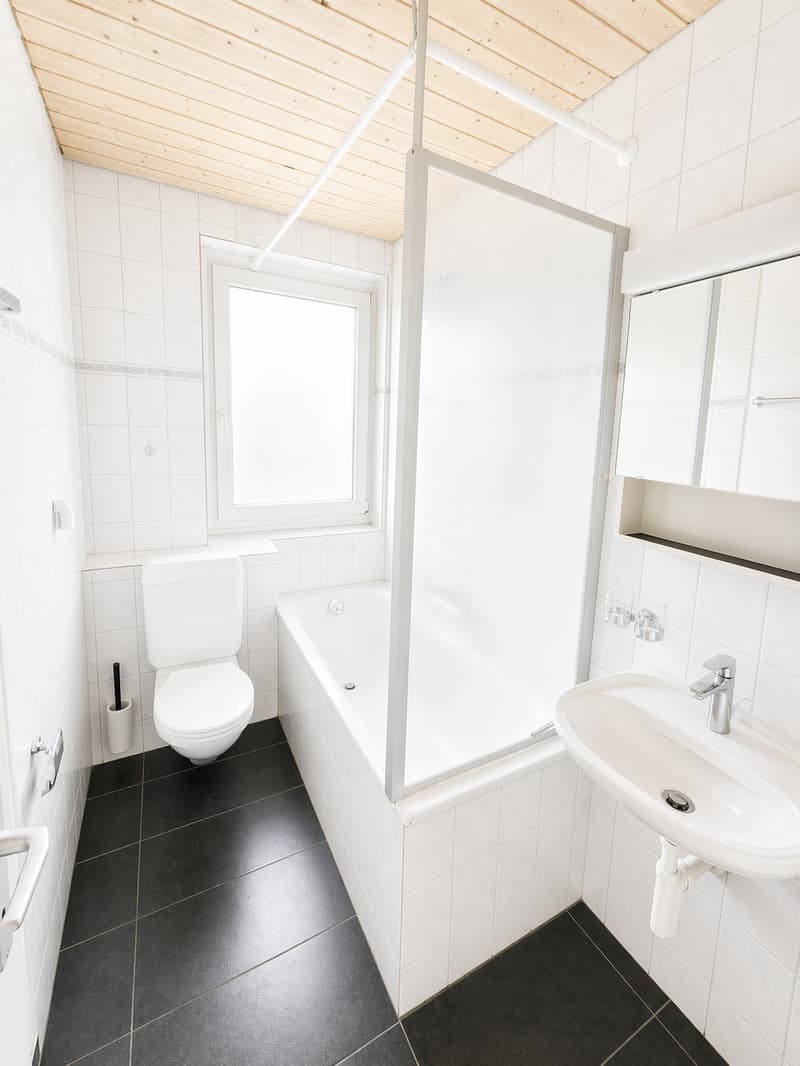 white tiles, white bathtub, white toilet, white sink, white mirror, wooden ceiling