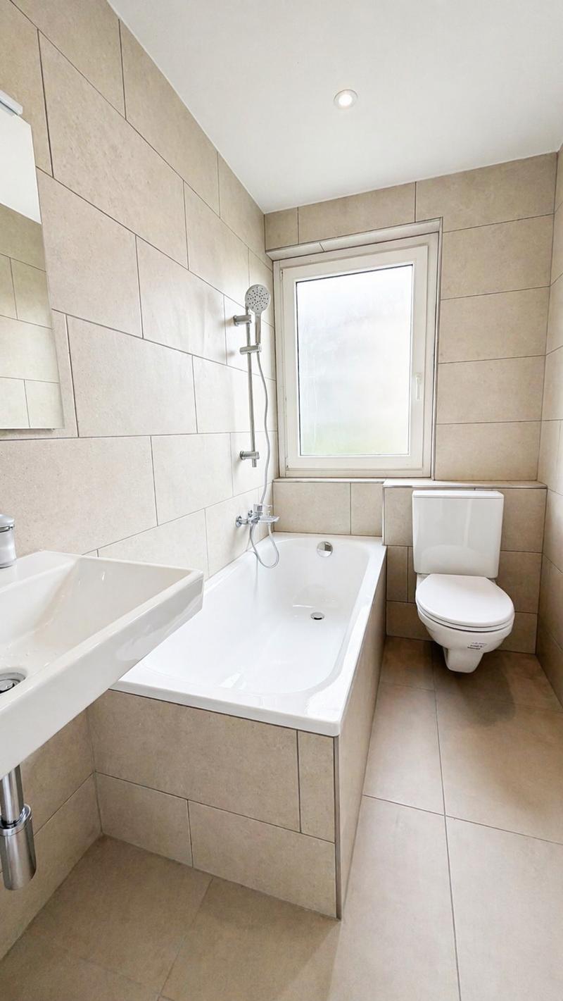Bathroom with bathtub, toilet, sink, and window