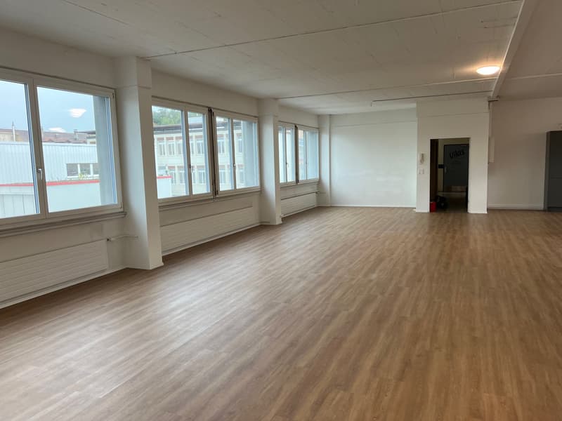spacious room with wooden floors, large windows, and white walls