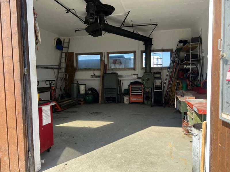 Garage with various tools and equipment, ladders, storage boxes, and a red trolley