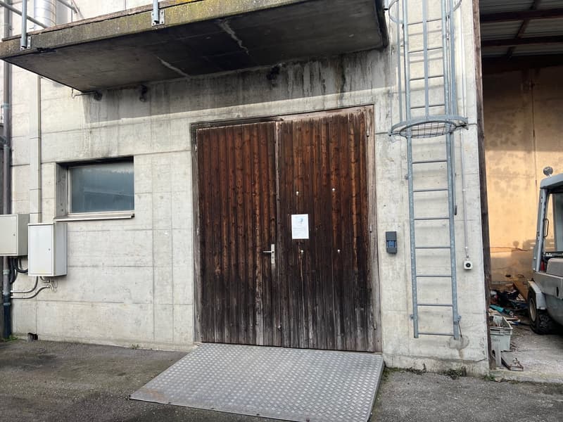 concrete building, wooden double doors, metal ladder, small balcony, metal ramp