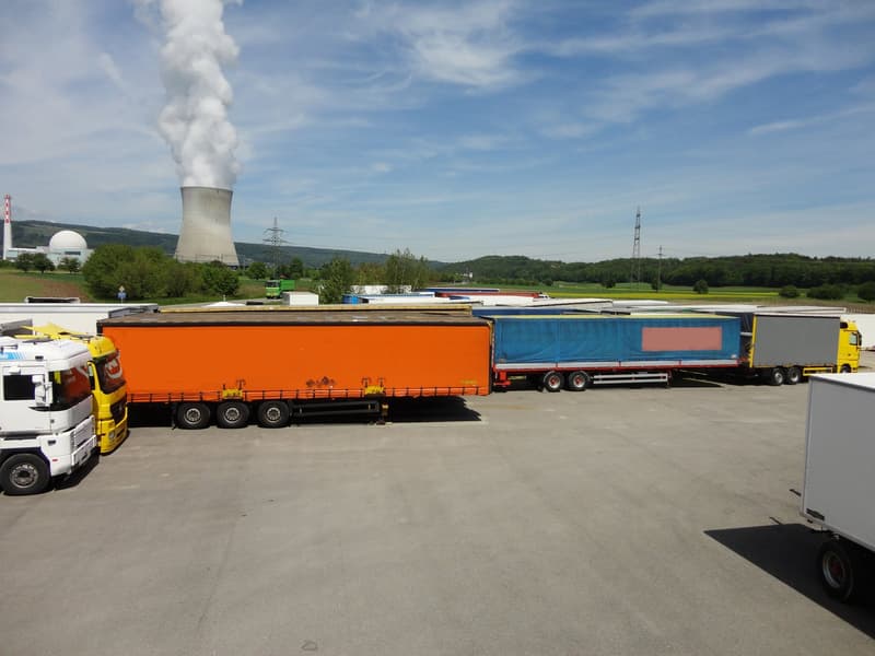 a large parking lot for trucks, power plants in the distance