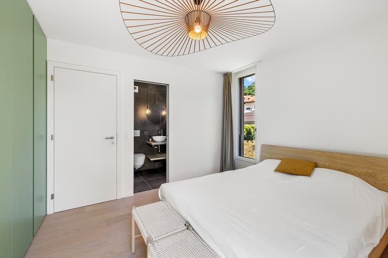 Chambre 1 avec accès direct à la salle d'eau / a modern bedroom with a white bed, a large window, and a door that leads to the bathroom