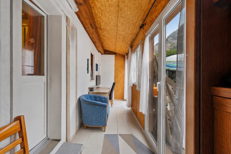 Espace donnant accès à la terrasse / a hallway with a blue chair and door to a balcony in a house