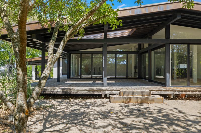 Villa avec baies vitrées offrant une vue paisible / a modern home with a large deck on a sunny day