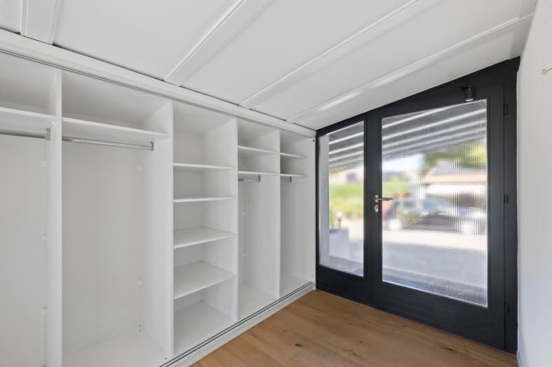 Entrée de la maison avec grande armoire murale intégrée / an empty walk - in closet with white shelving and sliding doors in a home