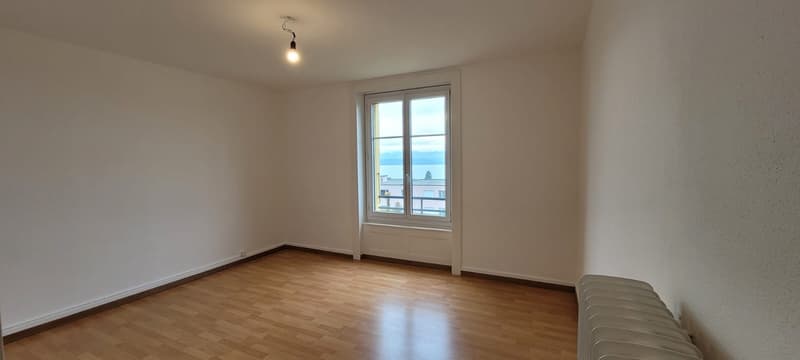 white walls, wooden floor, a large window with a view