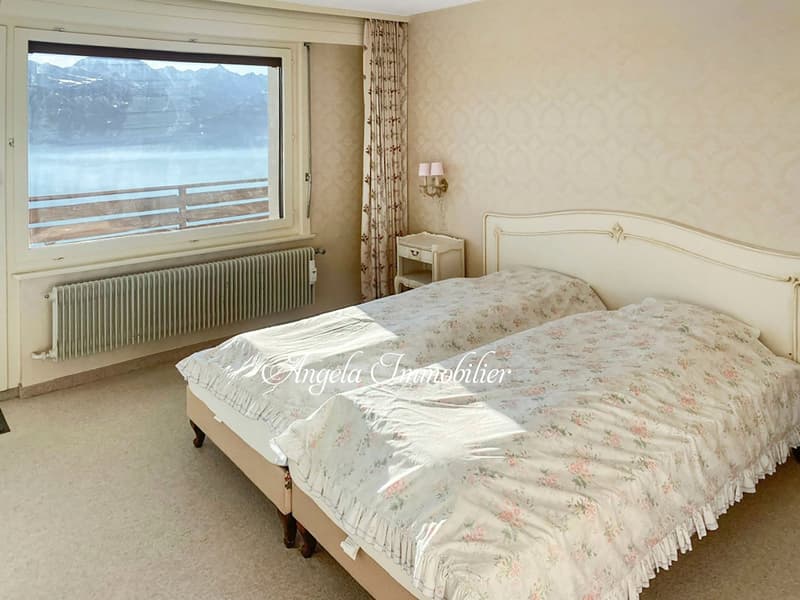 Two beds, large window with view, radiator, nightstand, lamp, floral bedspread
