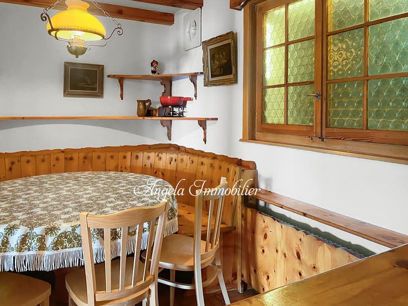 Dining area with wooden table, chairs, bench, and a window with glass panels