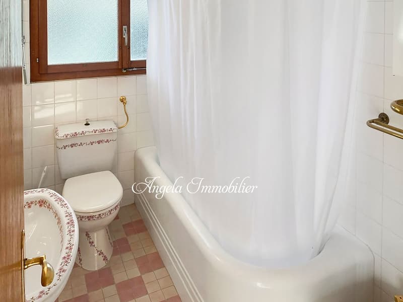 white bathtub, white toilet, white sink, white tiles, window
