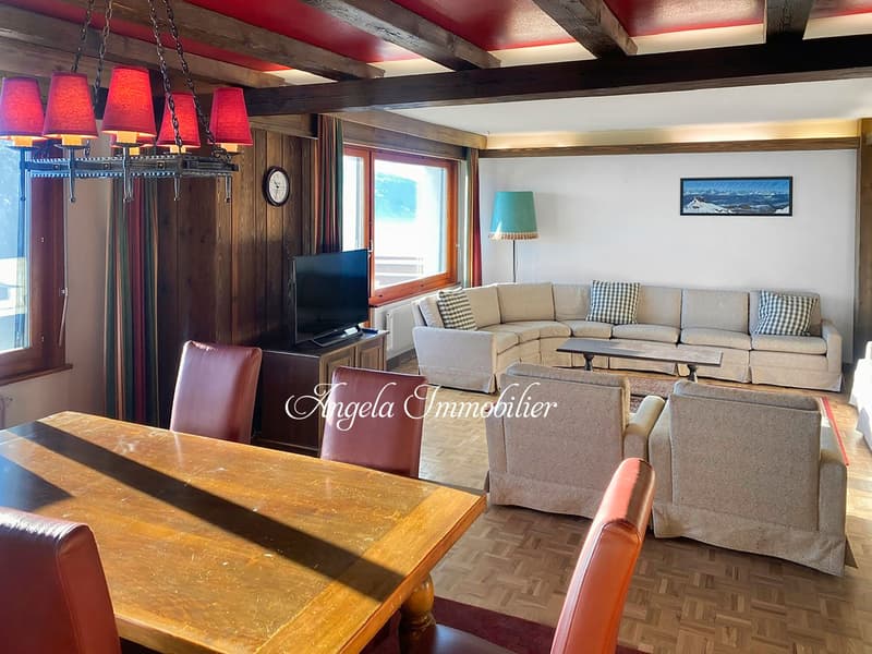 living room with wooden floor, wooden beams, large windows, sofa, dining table, TV, lamp, picture frame