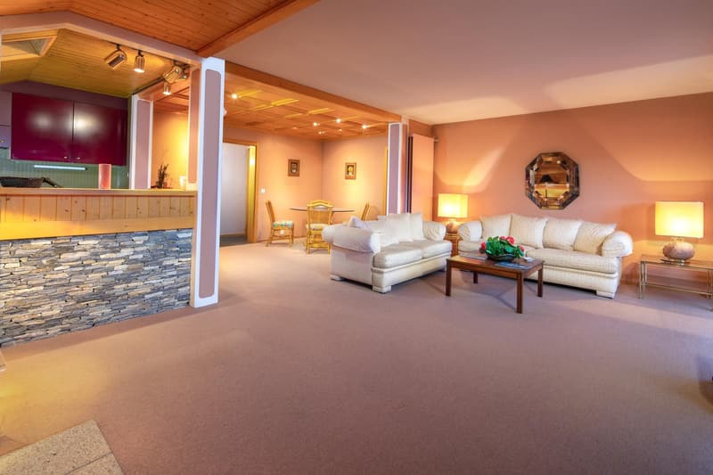 living room with two couches, coffee table, lamps, dining table, chairs, stone wall, wooden ceiling