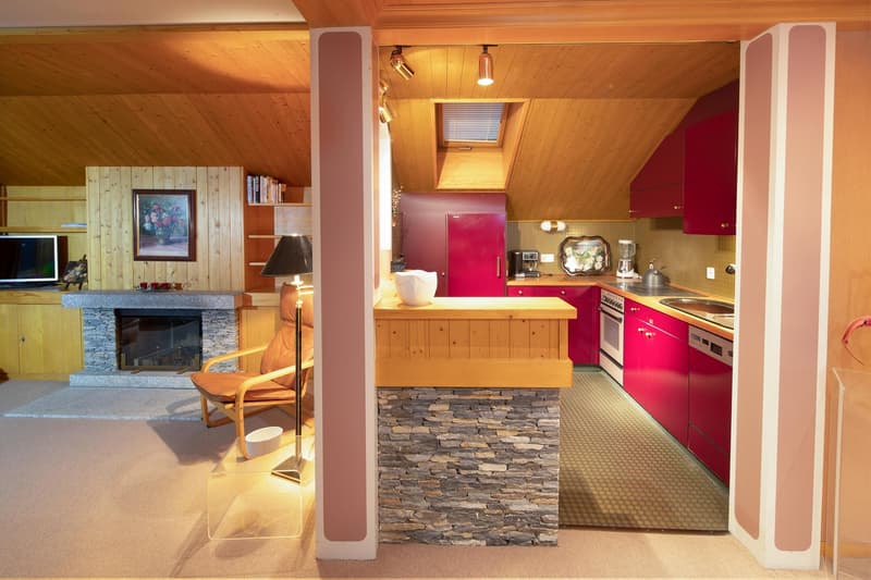 open kitchen, fireplace, wooden ceiling, red cabinets, stone wall, carpeted floor