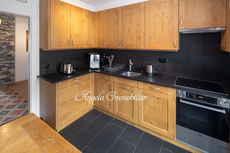 modern kitchen with wooden cabinets, black countertops, stainless steel appliances, black tiled floor, rug, electrical outlets