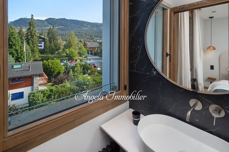 Bathroom with a large window, modern design, white sink, black marble wall, mirror, and a view of the mountains