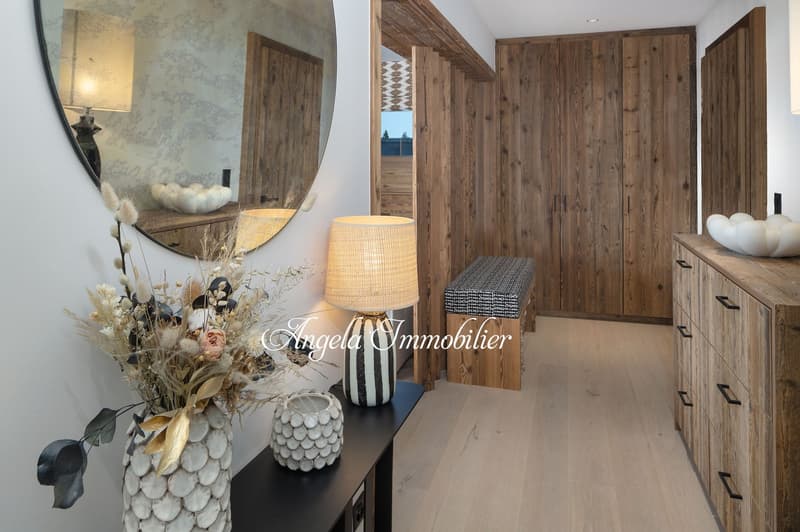 wooden wall, wooden floor, round mirror, lamp, bench, wooden cabinet, vase with flowers