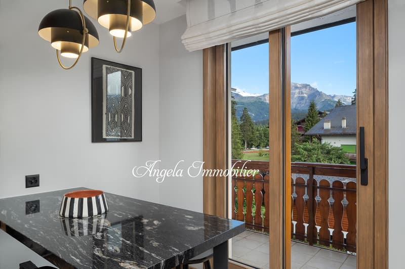 modern dining area with marble table, black and white bowl, large sliding glass door, balcony, wooden railing, mountain view